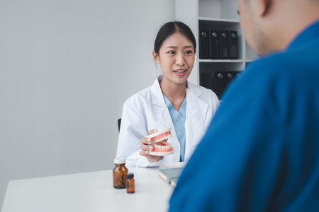 Female dentist explaining patient's teeth undergoing dental check-up, dentist giving advice on...