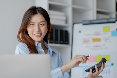 Asian woman sitting in startup company office, businesswoman, executive and investor in business and stocks, management of young people, new concept. Start-up company management concepts.の写真素材