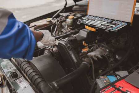 Car mechanic is inspecting the engine of a car coming in for repair at the center. Professional engine specialist, car repair, car breakdown. Car maintenance and repair concept.の写真素材