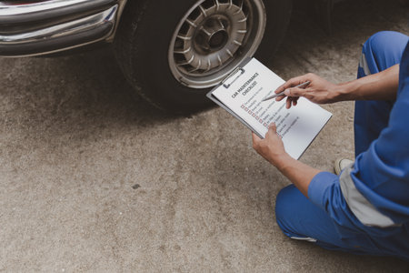 Car mechanic is inspecting tires and replacing worn tires through long hours of work, car repairs, car breakdowns, punctured tires. Concept of car tire maintenance and car repair.の写真素材