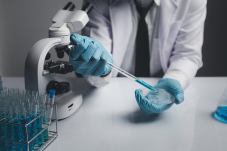 Lab assistant, a medical scientist, a chemistry researcher holds a glass tube through the blood sample, does a chemical experiment and examines a patient's blood sample. Medicine and research concept.の写真素材