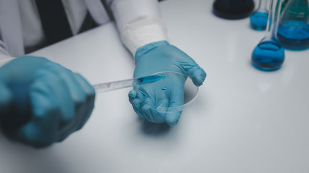 Lab assistant, a medical scientist, a chemistry researcher holds a glass tube through the blood sample, does a chemical experiment and examines a patient's blood sample. Medicine and research concept.の写真素材