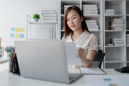 Young Asian woman, businesswoman in finance, businesswoman working in finance, planning finances for a startup company and reviewing financial statements. Financial management concepts.の写真素材