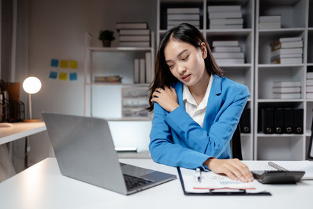 Asian women are stressed and tired from long hours of work, and businesswomen work hard causing office syndrome that often occurs in working people. The concept of office syndrome.の写真素材