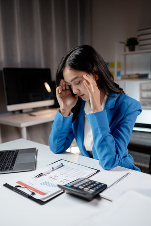 Asian women are stressed and tired from long hours of work, and businesswomen work hard causing office syndrome that often occurs in working people. The concept of office syndrome.の写真素材