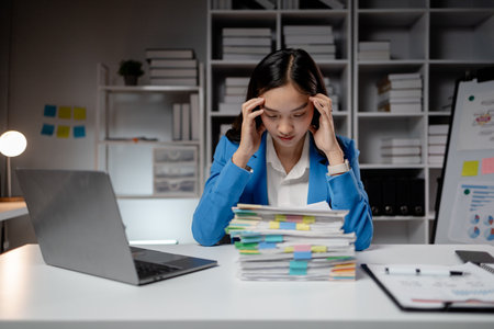 Asian women are stressed and tired from long hours of work, and businesswomen work hard causing office syndrome that often occurs in working people. The concept of office syndrome.の写真素材
