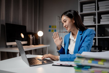 Asian woman is in office of a startup company, young businesswoman is giving a presentation via online video call to group of company executives, presenting a management budget. Online meeting ideas.の写真素材