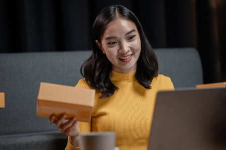 An online business owner, she sells products on a website and manages an online store on the Internet, taking orders and packing products for delivery to customers with a private courier service.の写真素材