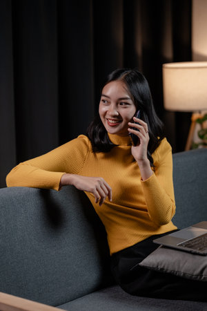 Asian woman relaxing on sofa in house, businesswoman spends her vacation watching movies, listening to music and surfing social media on smartphone, texting and chatting with friends. Weekend concept.の写真素材