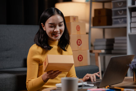 An online business owner, she sells products on a website and manages an online store on the Internet, taking orders and packing products for delivery to customers with a private courier service.の写真素材