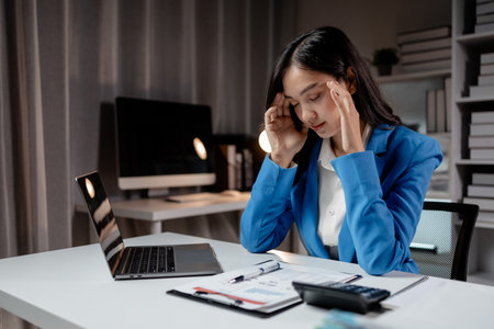 Asian women are stressed and tired from long hours of work, and businesswomen work hard causing office syndrome that often occurs in working people. The concept of office syndrome.の写真素材