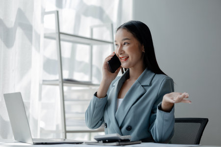 Businesswoman talking on the phone, business communication, telephone communication, Asian businesswoman working in a financial consulting service company, telephone consultation.の写真素材
