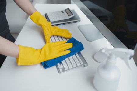 Cleaning staff wiping down office equipment, Wipe the keyboard clean with a towel and disinfectant....