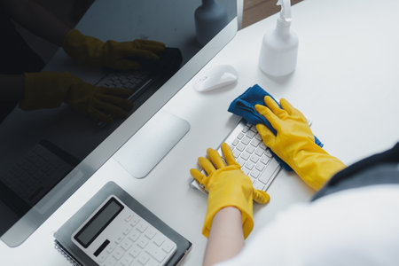 Cleaning staff wiping down office equipment, Wipe the keyboard clean with a towel and disinfectant....