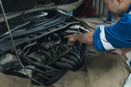 The mechanic is repairing the engine, A car repair worker is inspecting a car, A car mechanic is looking at what is the problem with the engine in the garage.の写真素材