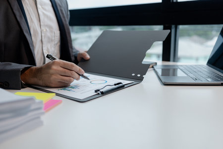 Working on laptop and looking at documents, Editing documents to send to customers, Review the documents for opening a startup company, Plan documents for attending the meeting.の写真素材