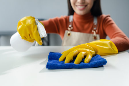 Cleaning desk surface in office with sanitizer spray, wear gloves and wipe the table with a towelの写真素材