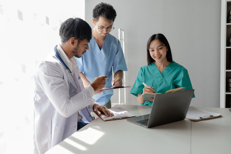 A group of male and female doctors sat and talked about the patient's history, There was a meeting about major surgery, The doctor takes the patient's documents and discusses them with team.の写真素材