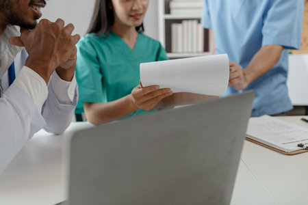 A group of male and female doctors sat and talked about the patient's history, There was a meeting about major surgery, The doctor takes the patient's documents and discusses them with team.の写真素材