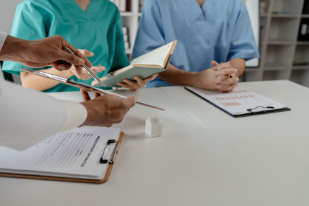 A group of doctors is brainstorming together in a conference room, There was a meeting about major surgery in the hospital, The doctor takes the patient's documents and discusses them with team.の写真素材