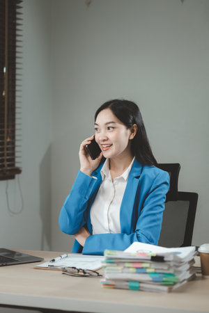 Businesswoman is talking on the phone with a partner, Businesswoman is sitting and working in the office, An entrepreneur is talking on the phone with a company customer, office idea.の写真素材