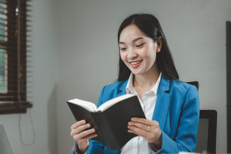 Business woman is sitting and working in the office, employee is looking for information on laptop, Recording various information on paper, office idea.の写真素材
