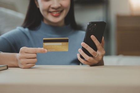 doing online shopping on the sofa in the living room, Use a credit card to make online payments while at home on day off, Use a laptop to enter a credit card information to pay for the service.の写真素材
