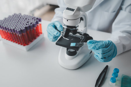 A chemist is using a microscope to search for chemicals from blood in a test tube, A scientific experiment is searching for biological answers in a laboratory, laboratory idea.の写真素材