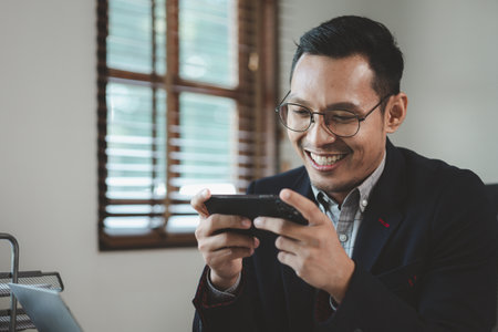 Businessman is working in the office and talking on the phone with a partner, Entrepreneurs use smartphones to find information in order to present it, Working in a private office at a company.の写真素材