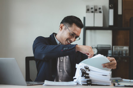 Businessman is sitting and working in the office, Employee is looking for information on laptop, An entrepreneur is talking on the phone with a company customer, startup.の写真素材