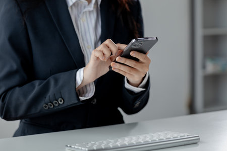 Businesswoman is working in the office and talking on the phone with a partner, Entrepreneurs use smartphones to find information in order to present it, Working in a private office at a company.の写真素材