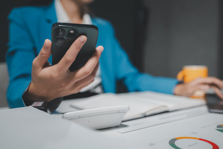 Beautiful woman in the office, happy, businesswoman uses internet phone close up, businesswoman checks email on smartphone, manager uses mobile phone, women in suit writes  message on smartphoneの写真素材