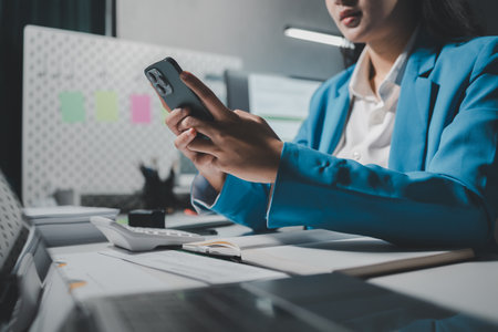 Beautiful woman in the office, happy, businesswoman uses internet phone close up, businesswoman checks email on smartphone, manager uses mobile phone, women in suit writes  message on smartphoneの写真素材
