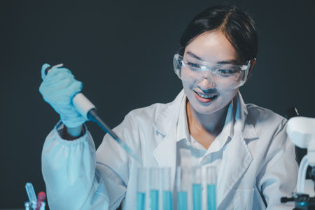 Young scientists in sterile clothing and safety goggles sitting at table conducting research...