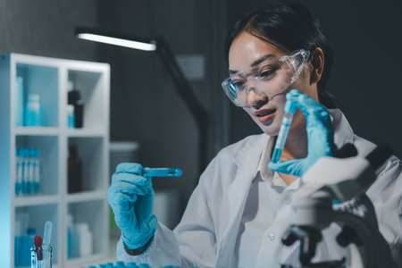 biochemical research scientist working with microscope for coronavirus vaccine development in, Portrait of a Beautiful Female Scientist in Goggles Using Micropipette for Test Analysis.の写真素材