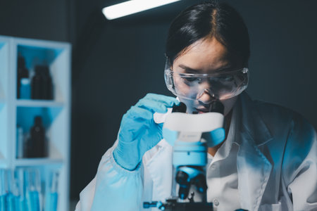 biochemical research scientist working with microscope for coronavirus vaccine development in,...