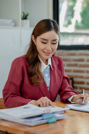 Numerical data is being presented for the accountant to calculate, Female accountant working about financial with calculator at her office, Savings, Finances and economy concept,の写真素材