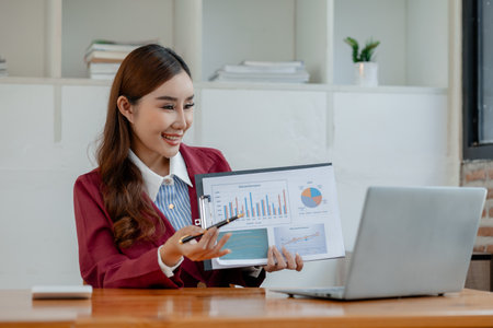 Woman entrepreneur giving presentation, businesswoman explaining graphs and data displayed on document, Businesswoman making a presentation to her colleagues via laptop.の写真素材