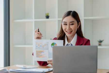Woman entrepreneur giving presentation, businesswoman explaining graphs and data displayed on document, Businesswoman making a presentation to her colleagues via laptop.の写真素材