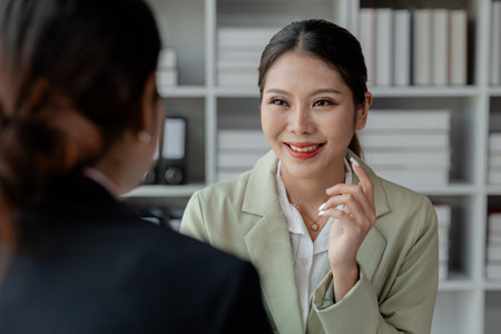 Two business colleagues working together on desktop computer at office, Colleagues problem solving at computer together, cheerful business people using a laptop in an office.の写真素材