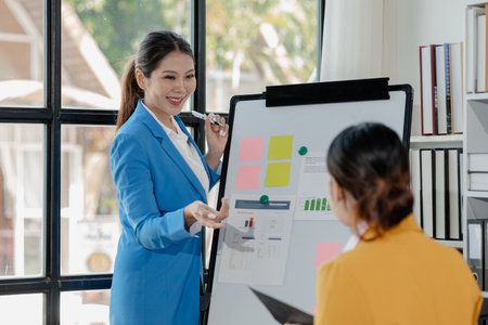 Confident female professional discussing with colleagues, Professional business executive managers working using laptop computer sitting at table, discussing digital strategy at corporate meeting.の写真素材