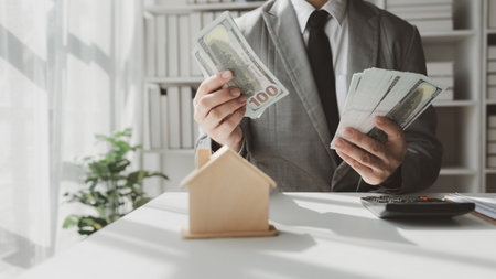 A real estate agent sits in his office, A business owner is counting money and making notes in a financial book, The financier is verifying the income received from the client's investment,の写真素材