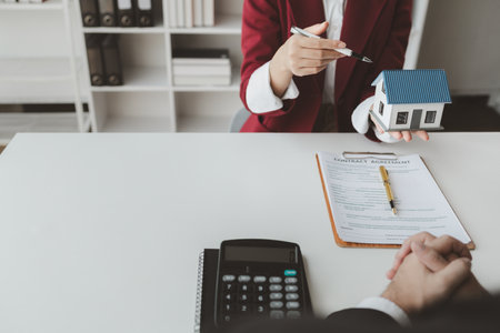 The broker is calculating the buyer's monthly instalment payments, Real estate broker agent presenting and consult customer to decision making sign insurance form agreement, buy and sell home model,の写真素材