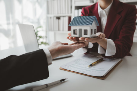 The broker is calculating the buyer's monthly instalment payments, Real estate broker agent presenting and consult customer to decision making sign insurance form agreement, buy and sell home model,の写真素材