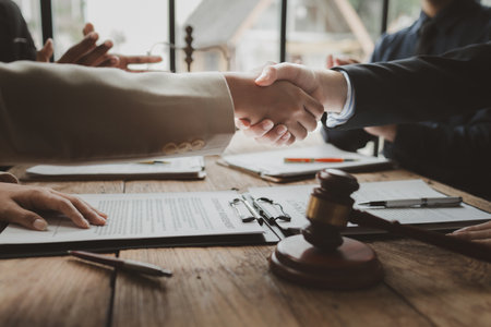 Crop shot of person with pen signing contract at desk in the office, Business people negotiating a contract, discussing contract while working together in sunny modern office, shaking hands.の写真素材