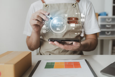Smartphones are being used to do various activities to promote sales to stores, owner of an online store packs products into parcel boxes based on orders from online sales sites.の写真素材