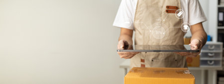 tablet are being used to do various activities to promote sales to stores, owner of an online store packs products into parcel boxes based on orders from online sales sites.の写真素材