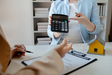 A realtor is explaining home insurance documents to a buyer in office at the company, Sign home insurance documents, make an agreement together, concerning mortgage loan offer for and house insuranceの写真素材