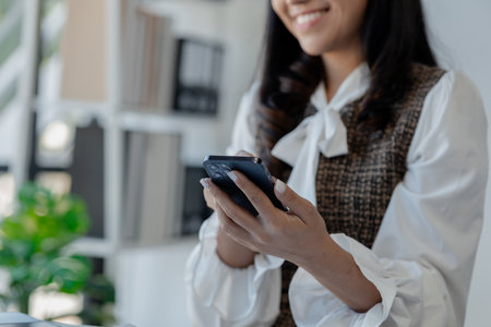 An entrepreneur is talking on the phone with a company customer, Beautiful woman in the office, happy, businesswoman checks email on smartphone, manager uses mobile phone,の写真素材