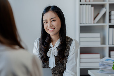 Two beautiful female colleagues interacting while working in office, business colleagues working together on desktop computer at office, Colleagues problem solving at computer togetherの写真素材